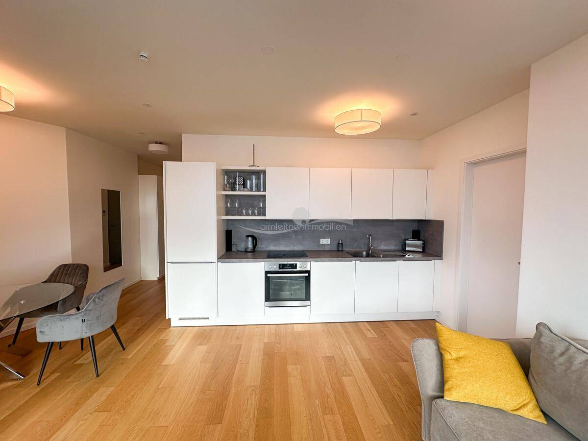 Moderne weiße Einbauküche mit Essbereich und offenem Übergang zum Wohnzimmer.