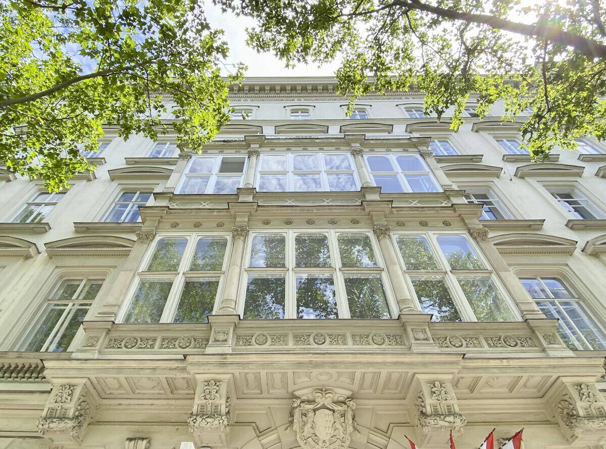 Prachtvolle Altbaufassade mit großen Erkerfenstern und detaillierten Verzierungen unter blauem Himmel.