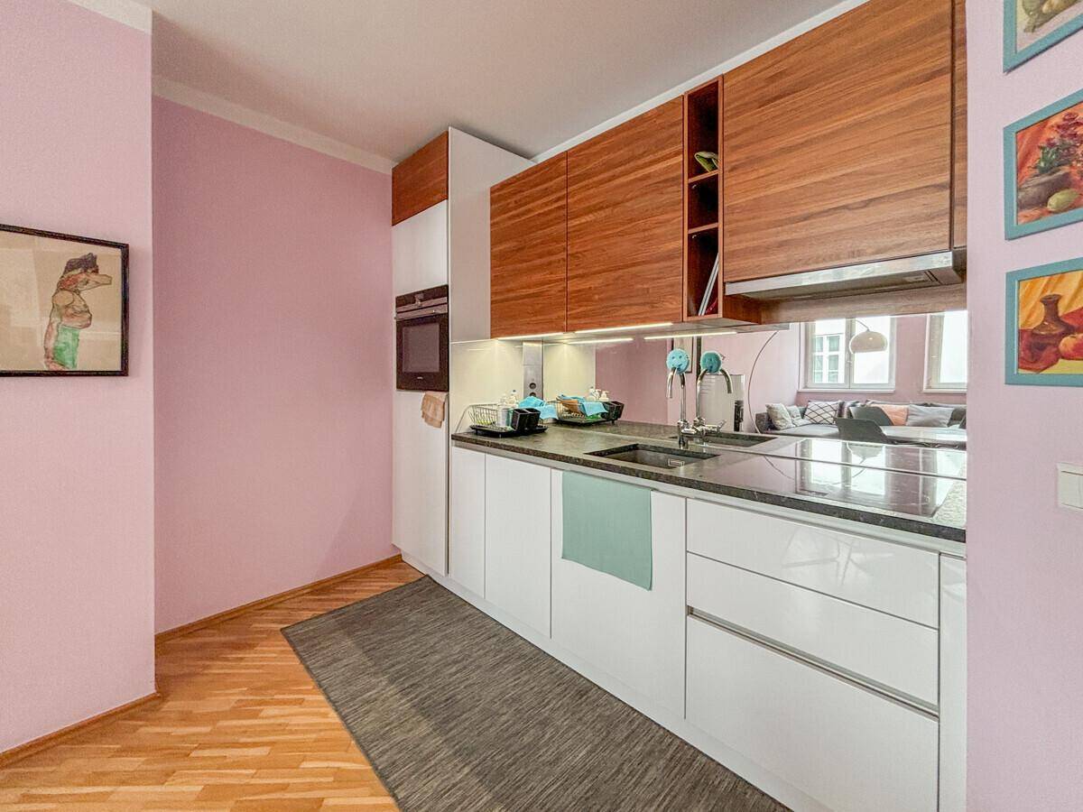 Moderne Küchenzeile mit weißen Unterschränken, Holzfronten und dunkler Arbeitsplatte.