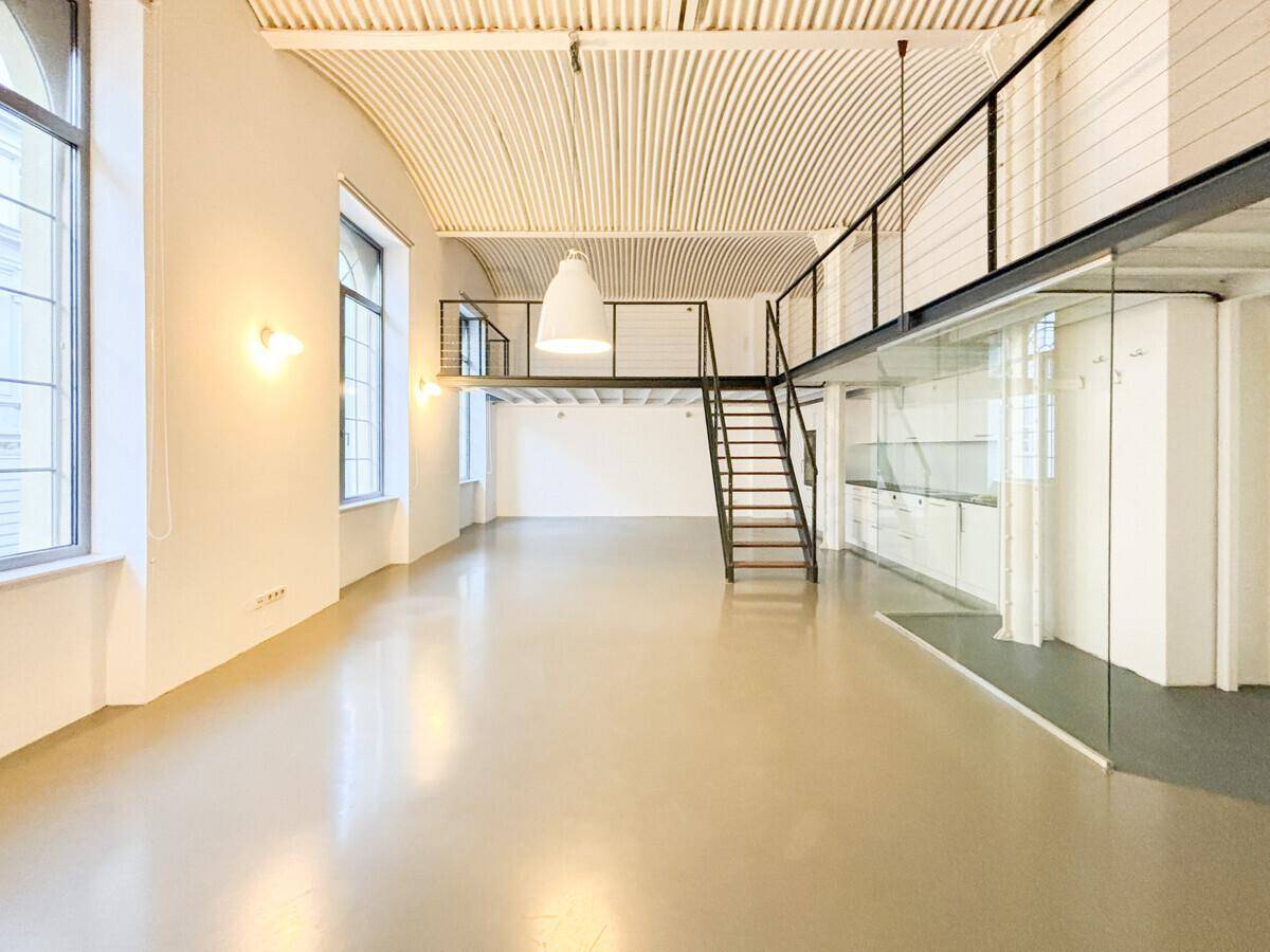 Geräumiger Loft-Wohnbereich mit hoher gewölbter Decke, Galerie und moderner Treppe.