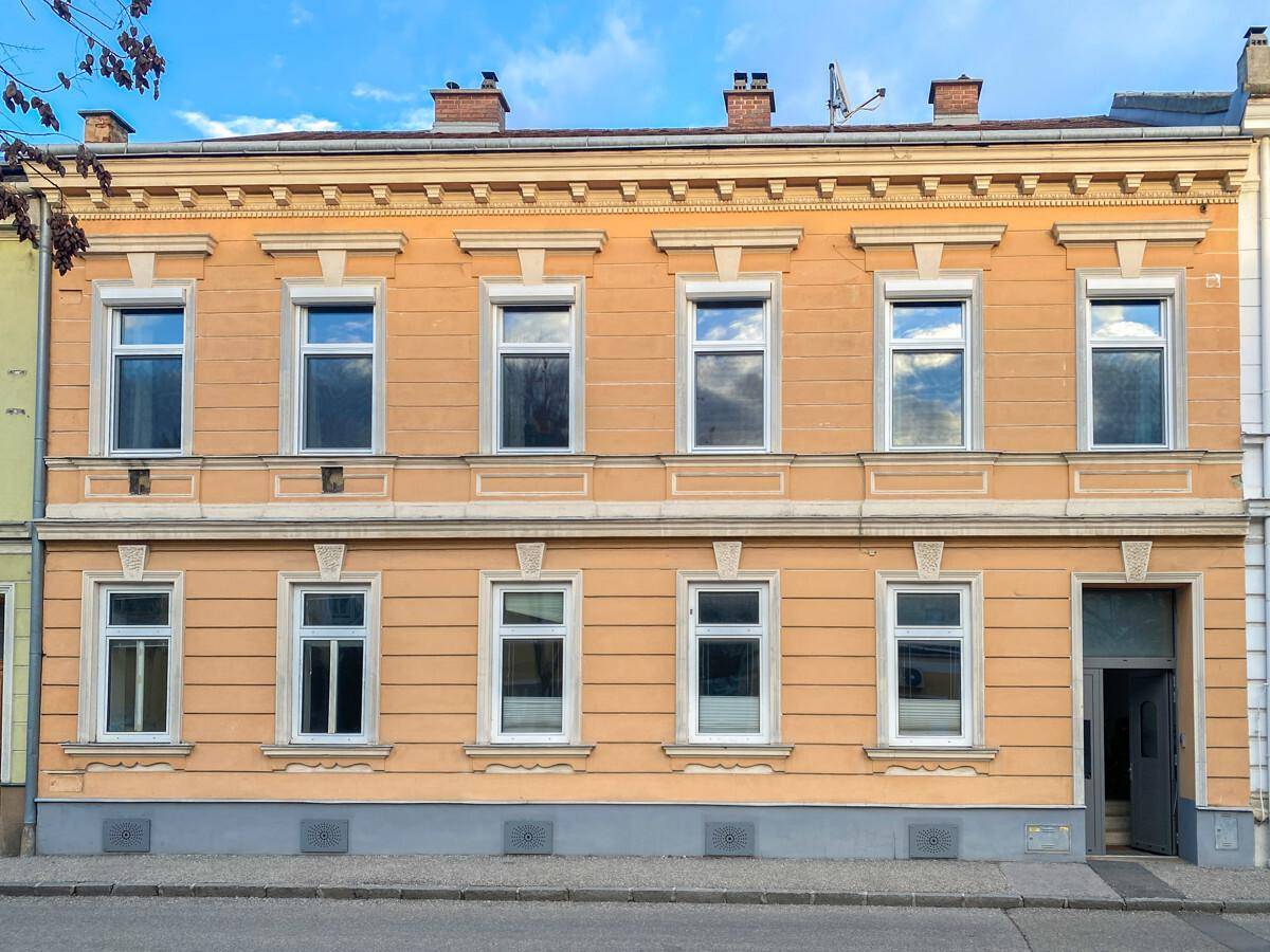 Klassische Fassade eines Altbaus mit vielen Fenstern und dekorativen Elementen.