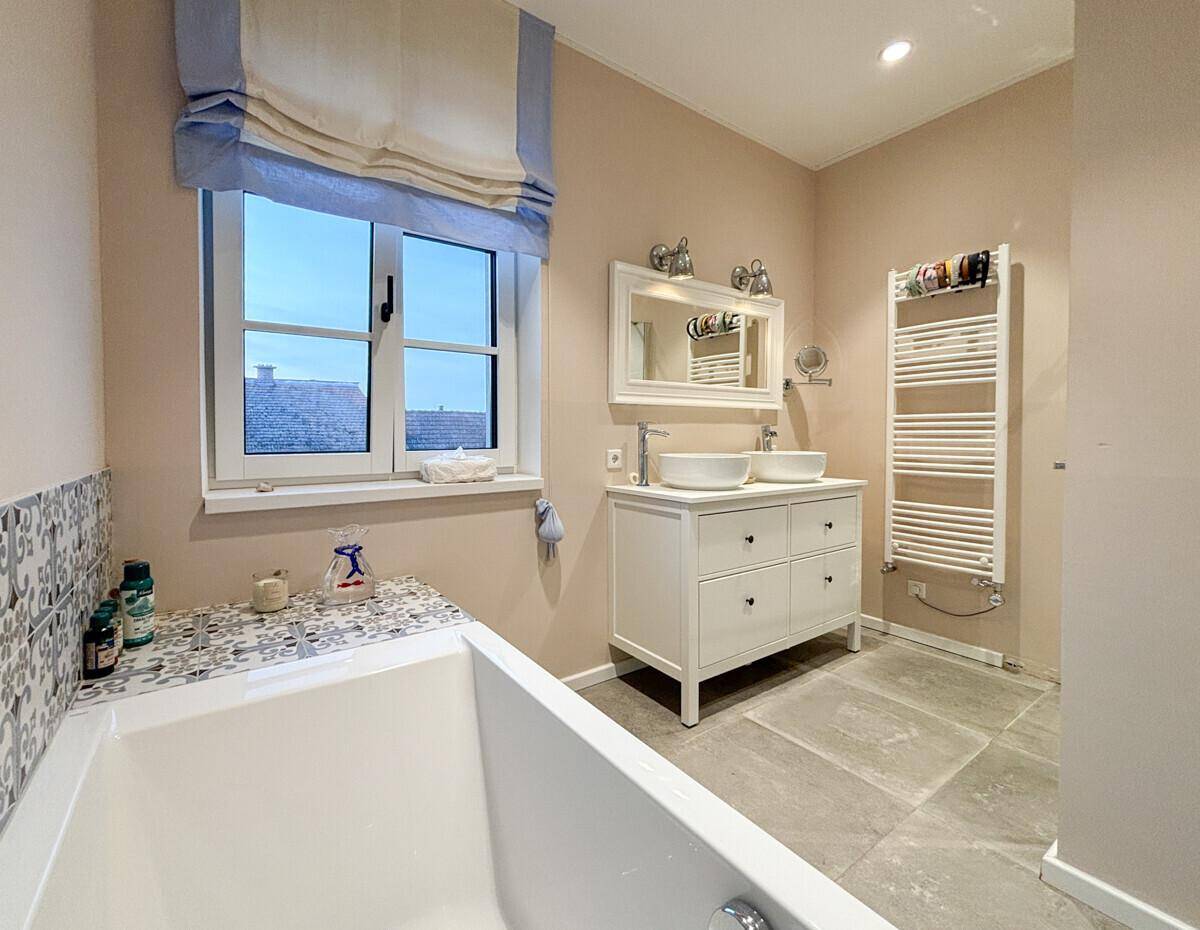 Modernes Badezimmer mit Badewanne, Doppelwaschbecken und beheiztem Handtuchhalter.