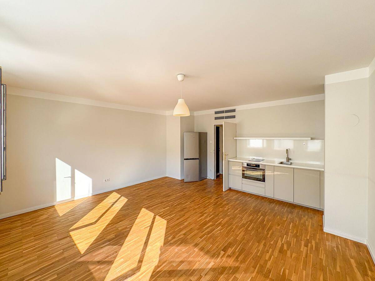 Heller Wohnbereich mit integrierter Küchenzeile, Kühlschrank und Ofen, ideal für ein offenes Wohnkonzept.