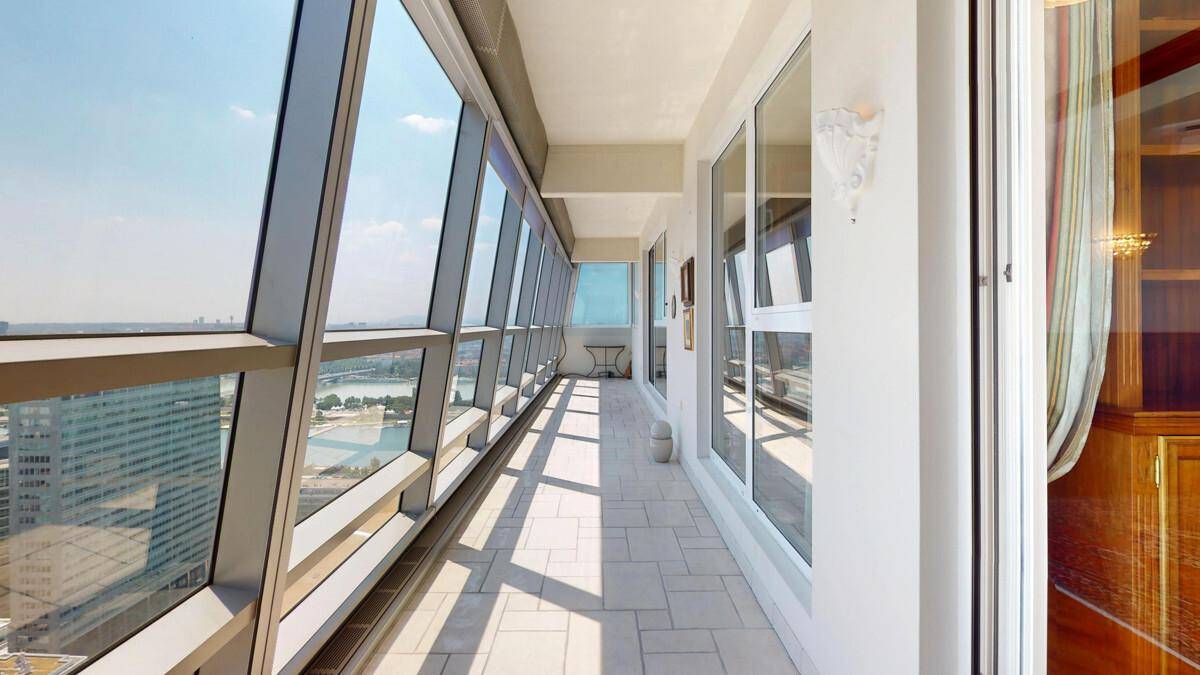Lange, verglaste Loggia mit Fliesenboden und weitem Stadtblick von oben.