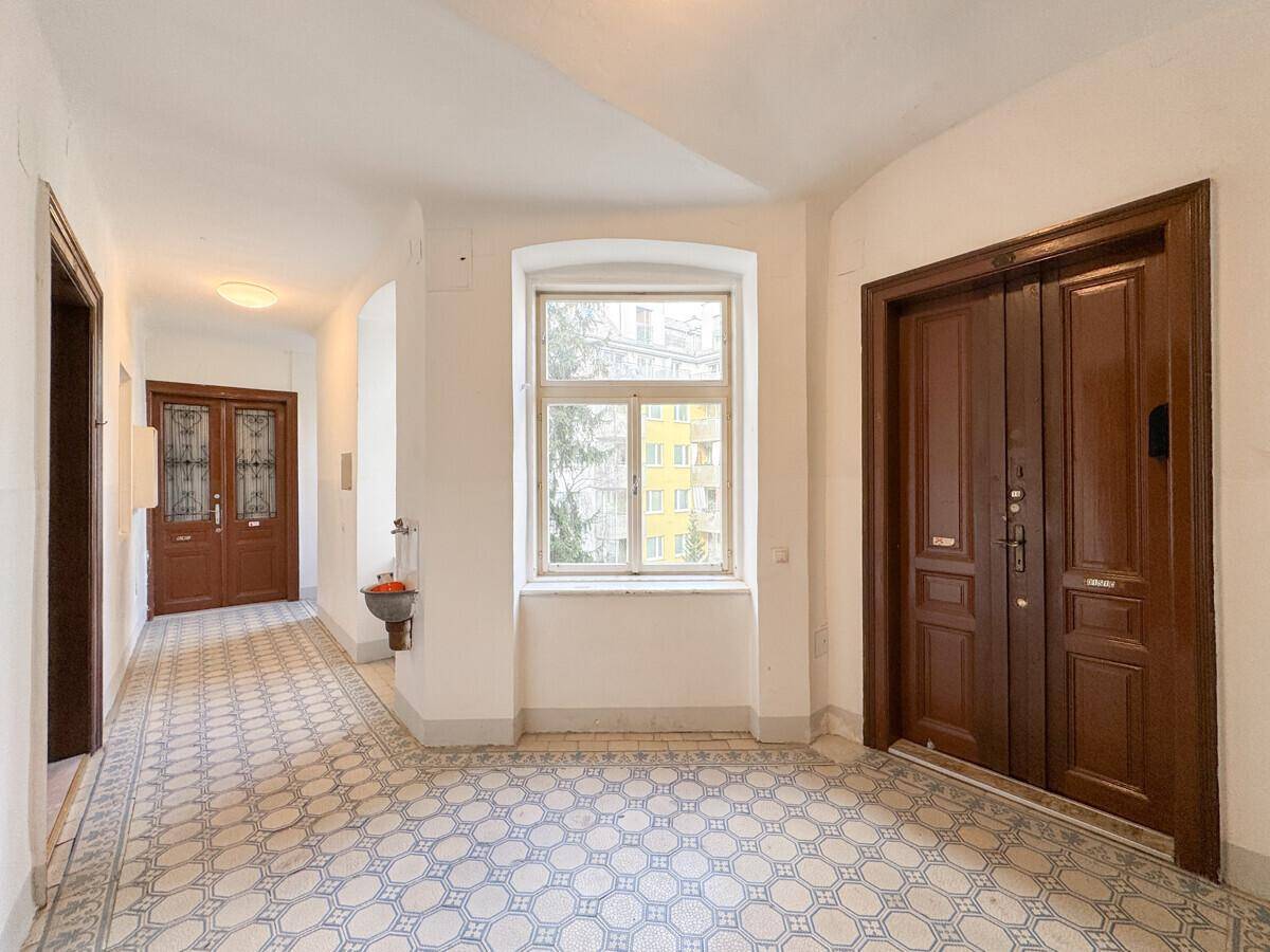 Heller Eingangsbereich mit gemusterten Fliesen und klassischen Holztüren, typisch für Altbauten.