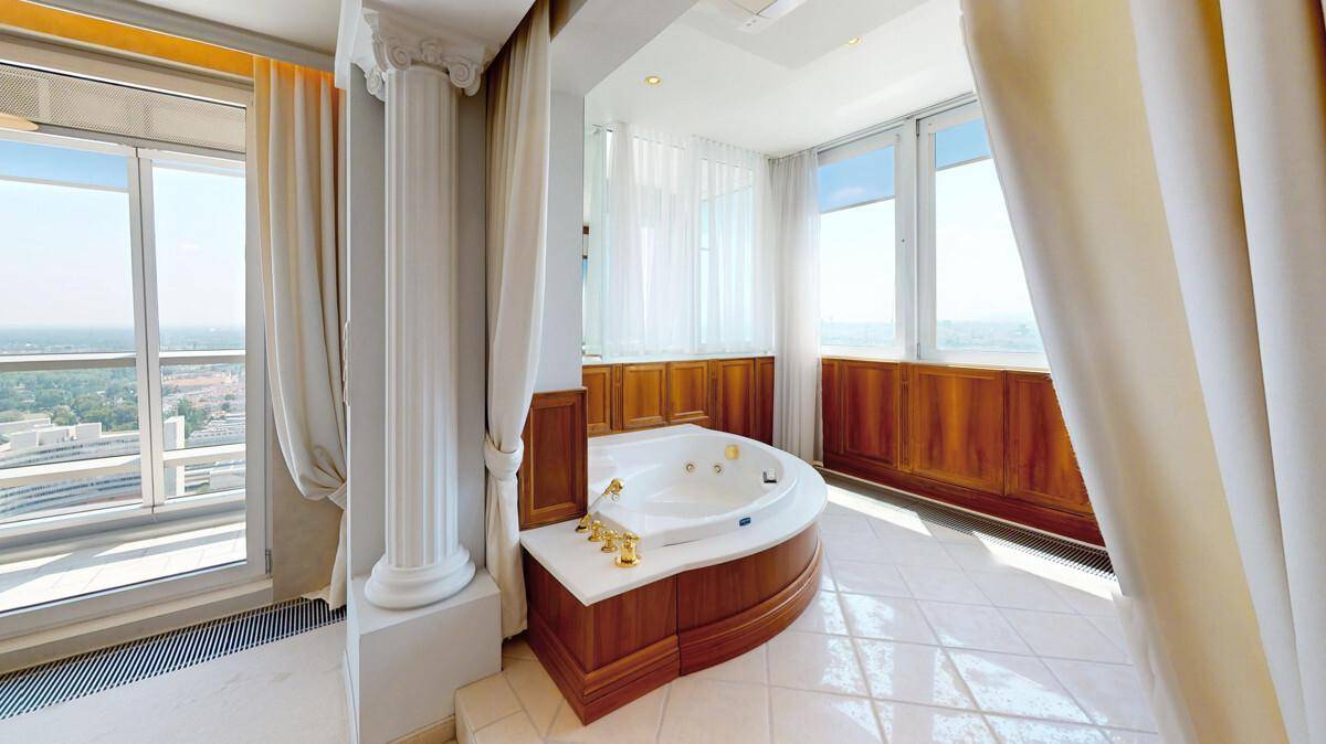 Luxuriöser Badebereich mit Eck-Whirlpool, Fliesenboden und Panoramablick.