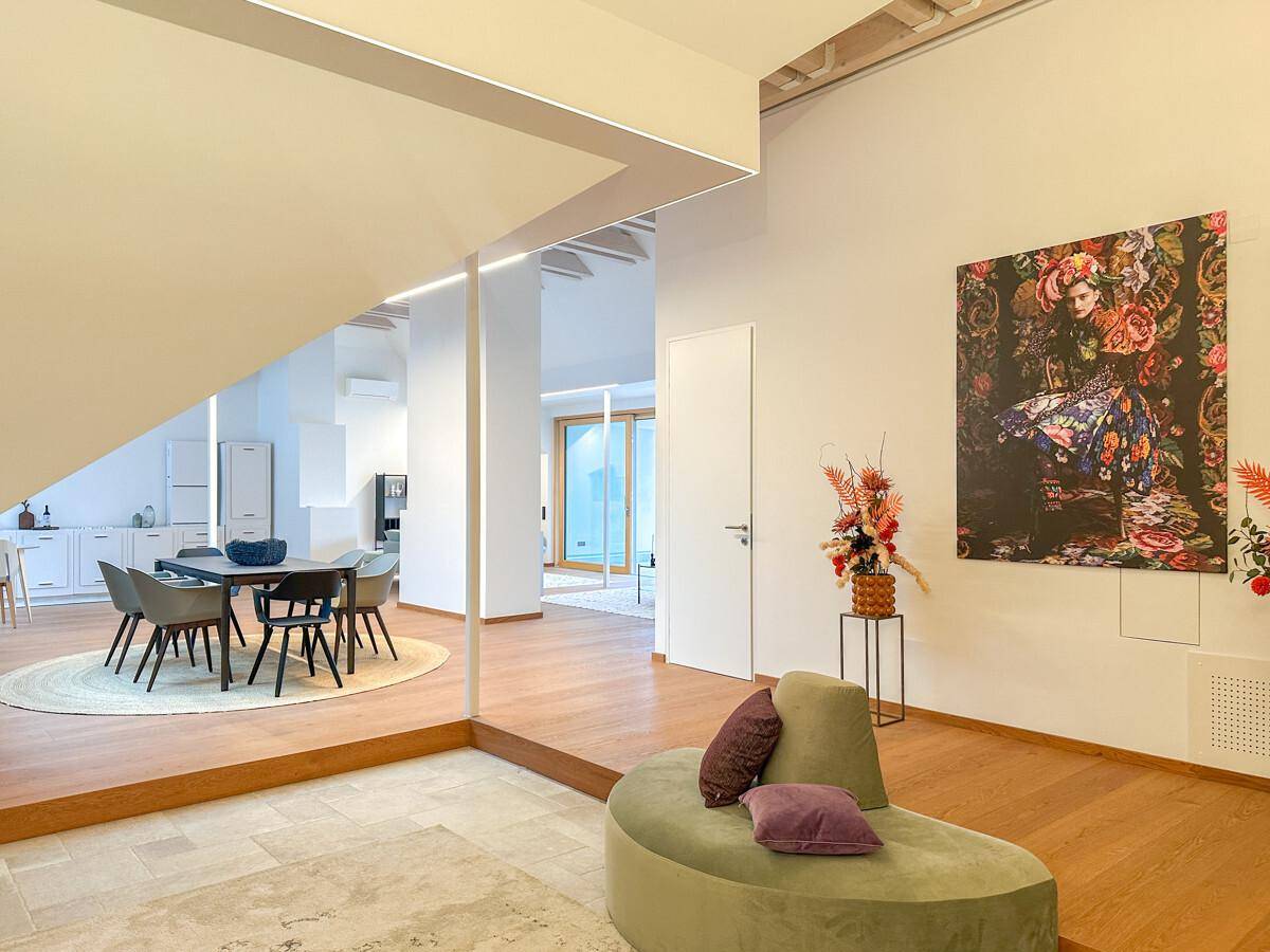 Moderner Essbereich mit Holzboden und künstlerischer Wanddekoration, offen zu weiteren Wohnbereichen.
