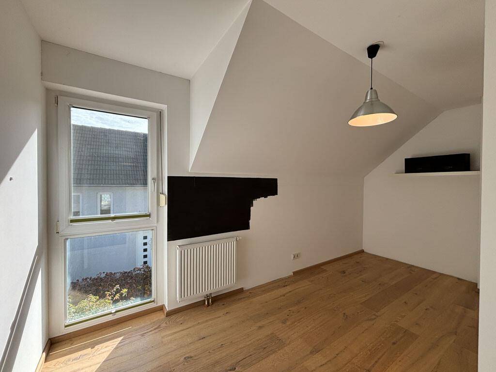 Helles Zimmer mit Holzboden, Fenster und Heizkörper, ideal als Kinder- oder Arbeitszimmer.