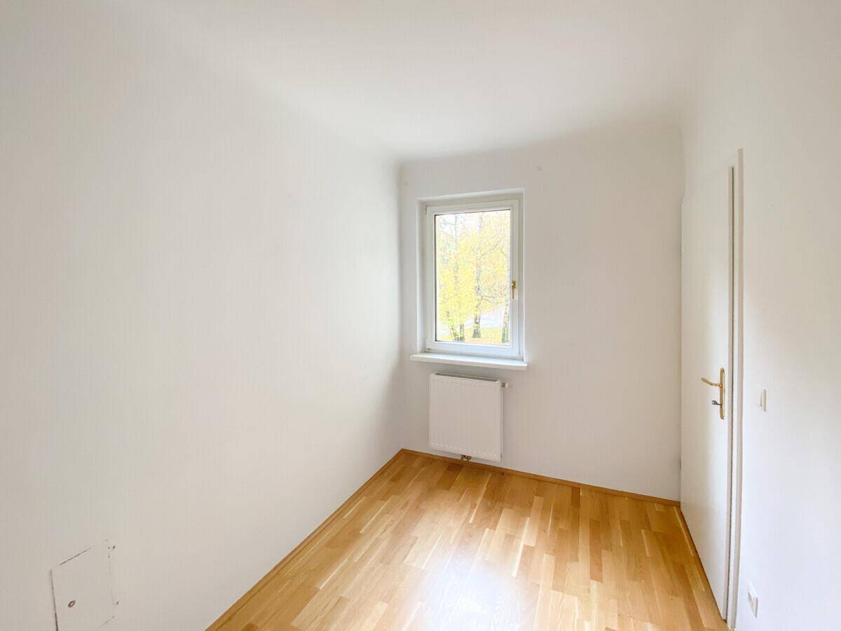 Kleineres, helles Zimmer mit Parkettboden, weißen Wänden und einem Fenster für natürliche Belichtung.