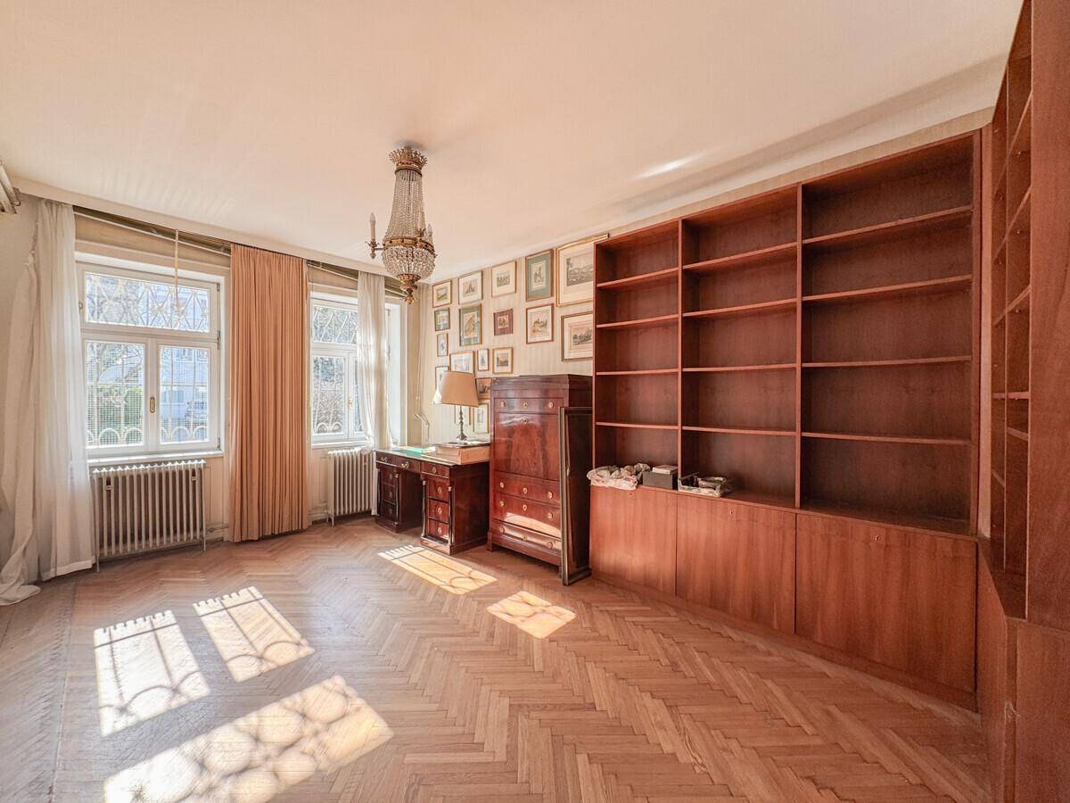 Elegantes Arbeitszimmer mit Fischgrätparkett, Einbauregalen und einem klassischen Kronleuchter.