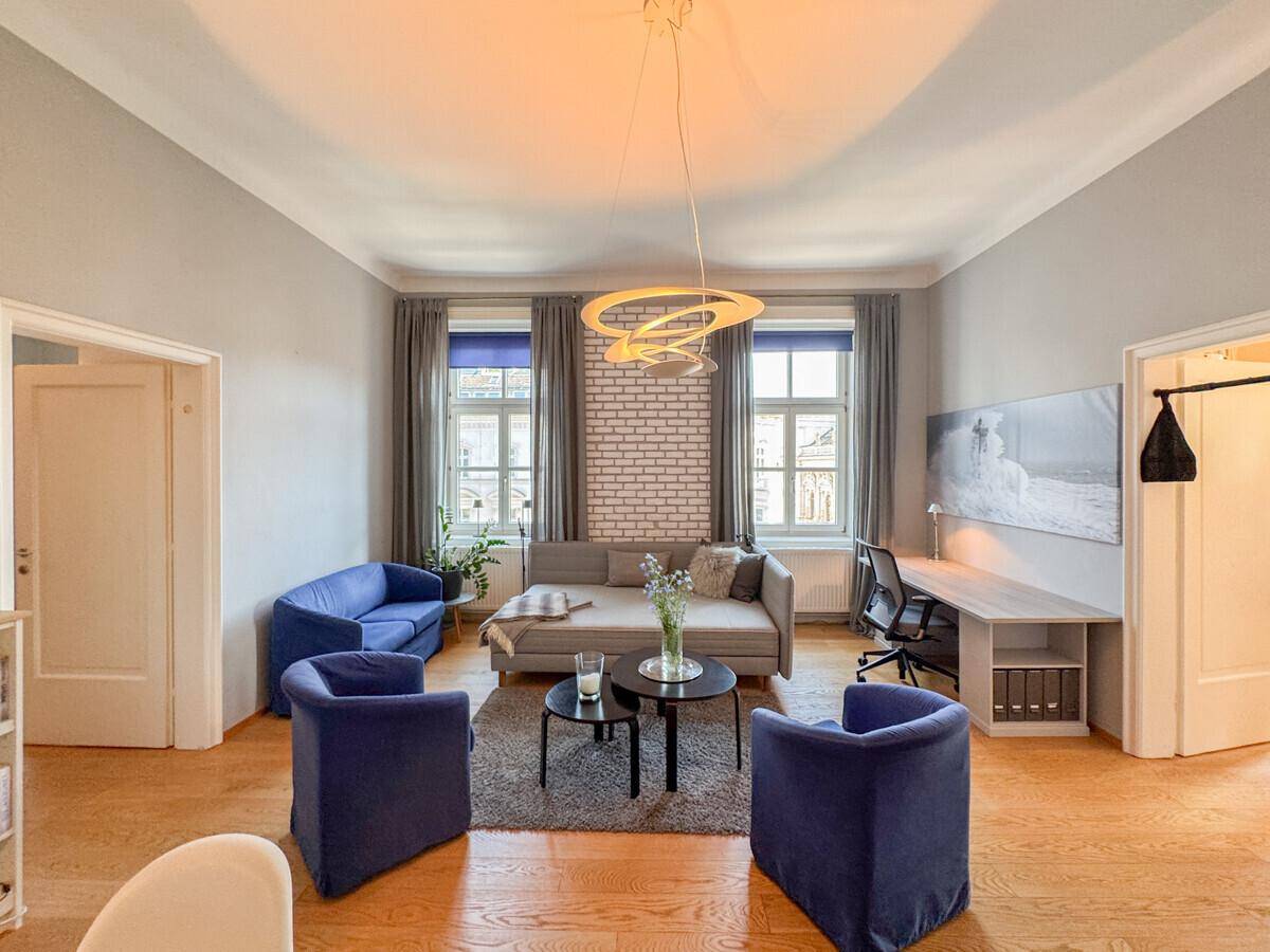Modern eingerichtetes Wohnzimmer mit Holzboden, Schreibtisch und dekorativer Ziegelwand.