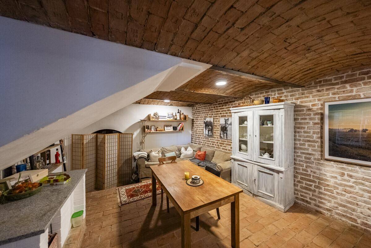 Gemütlicher Wohnbereich im Keller mit Ziegelwänden, Holztisch und Sofa, ideal für gesellige Abende.