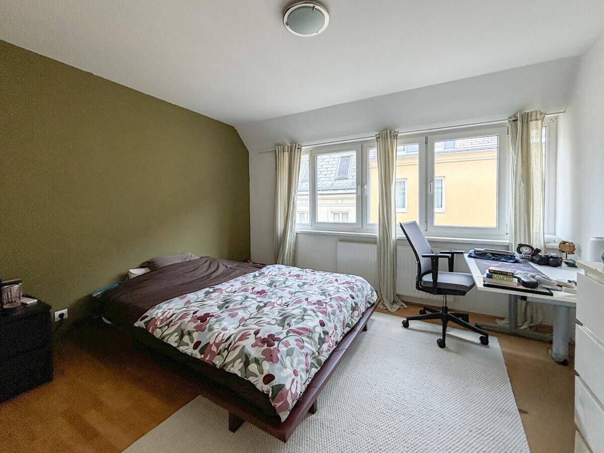 Gemütliches Schlafzimmer mit Doppelbett, Schreibtisch und einer grünen Akzentwand.