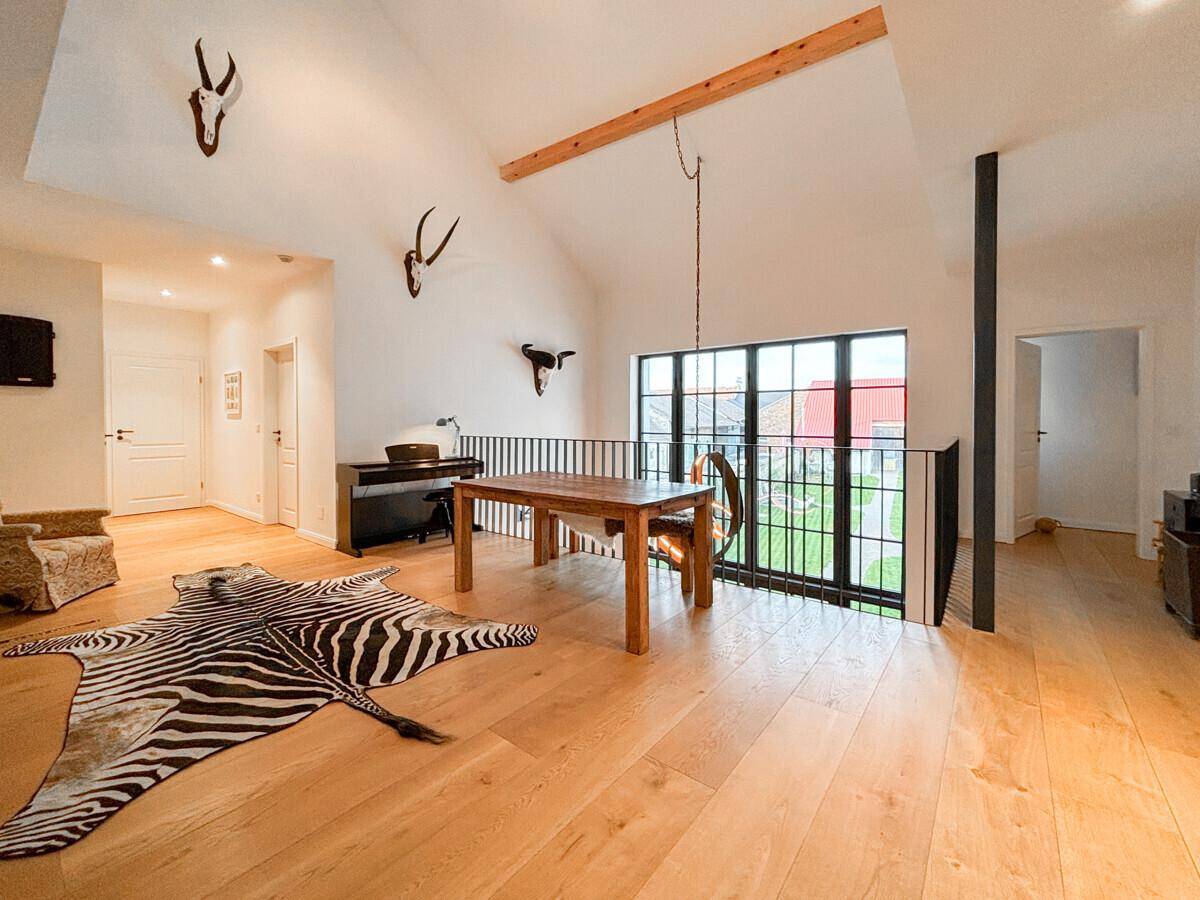 Offene Galerie mit hohen Decken, großen Fenstern und Holzboden, die einen hellen und luftigen Raum schafft.