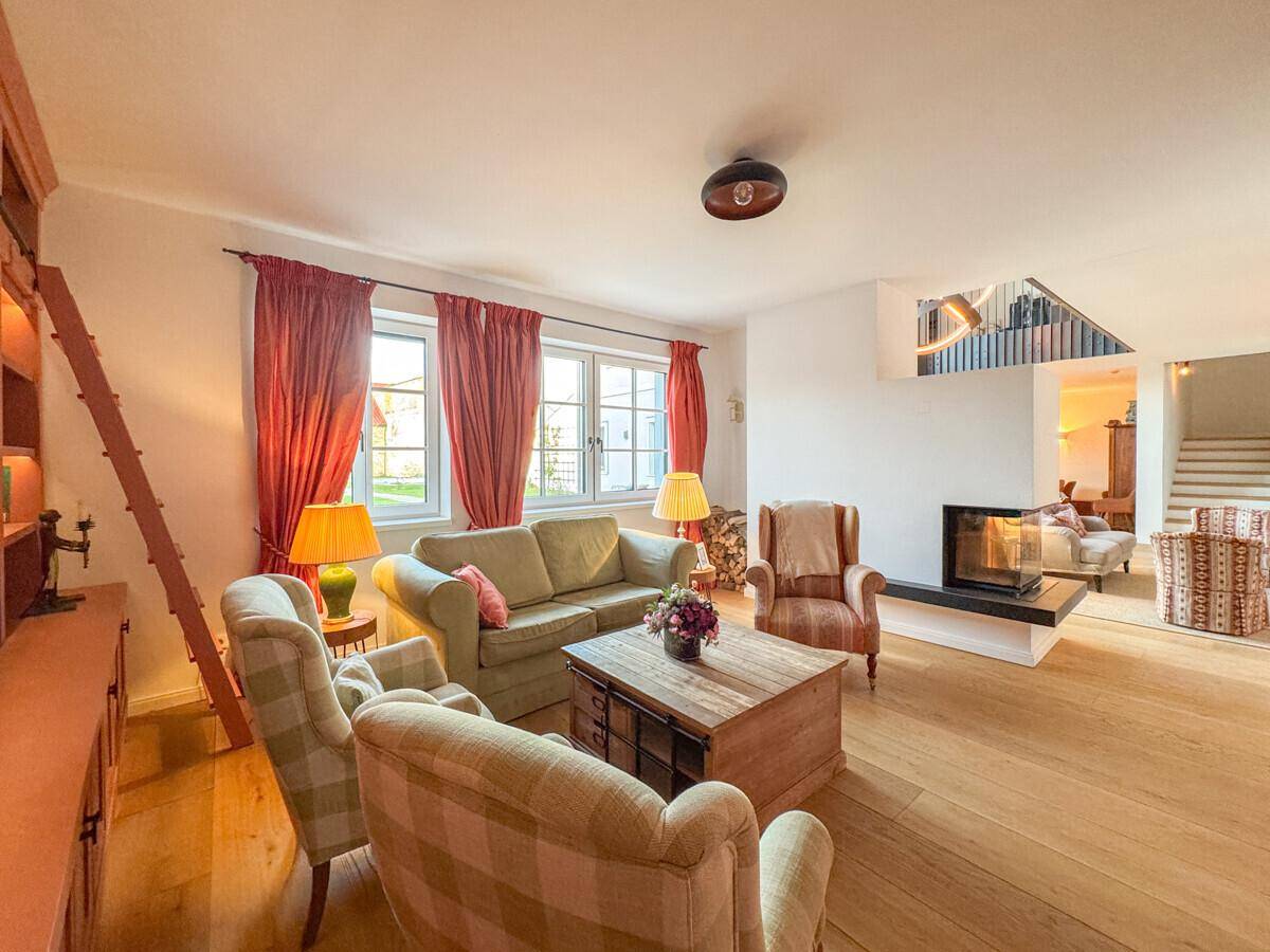 Gemütliches Wohnzimmer mit Kamin, Holzfußboden und traditionellen Möbeln, die eine warme Atmosphäre schaffen.