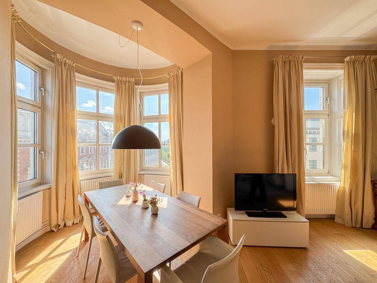 Gemütlicher Essbereich im Erker mit Holztisch und Blick auf die Stadt.