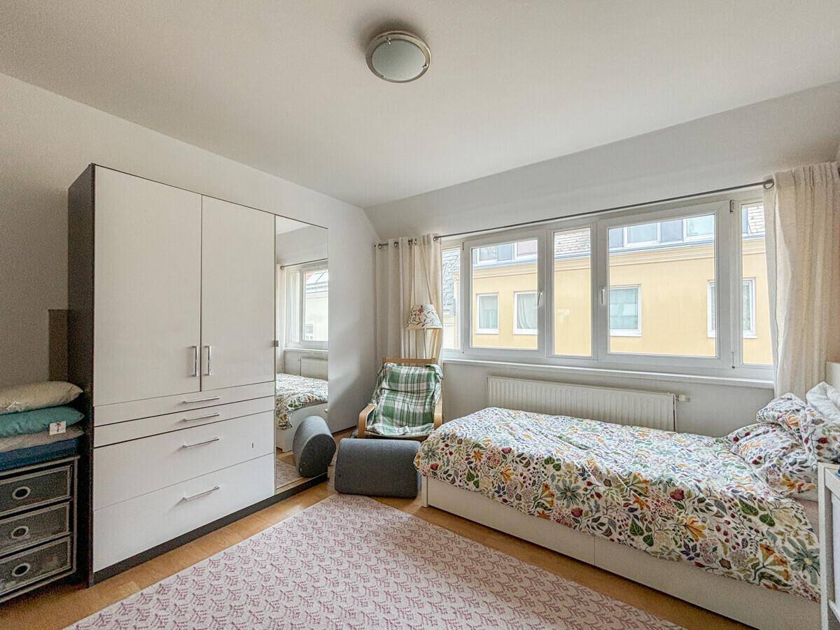 Helles Schlafzimmer mit Einzelbett, großem Kleiderschrank und viel Tageslicht.