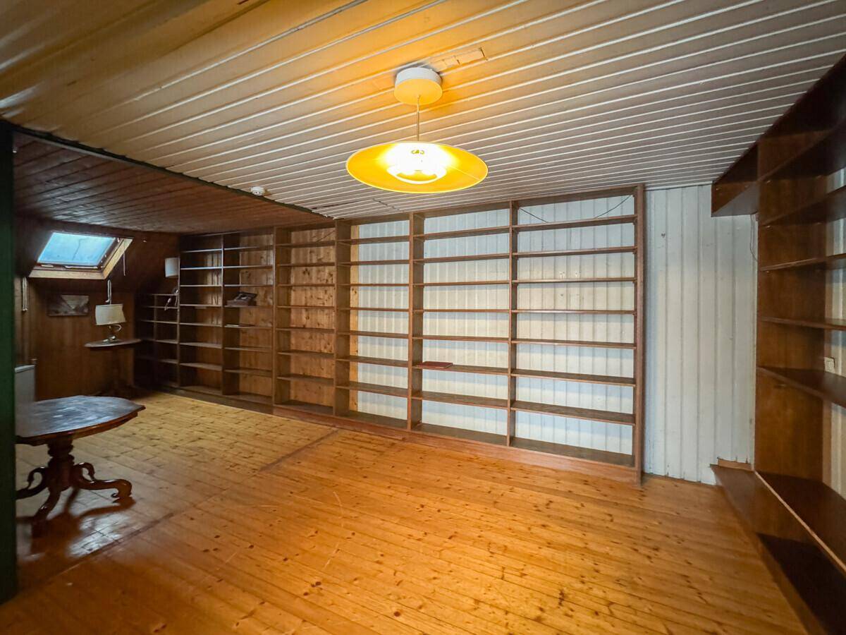 Gemütlicher Raum mit Holzvertäfelung, eingebauten Bücherregalen, Holzboden und einem Dachfenster.