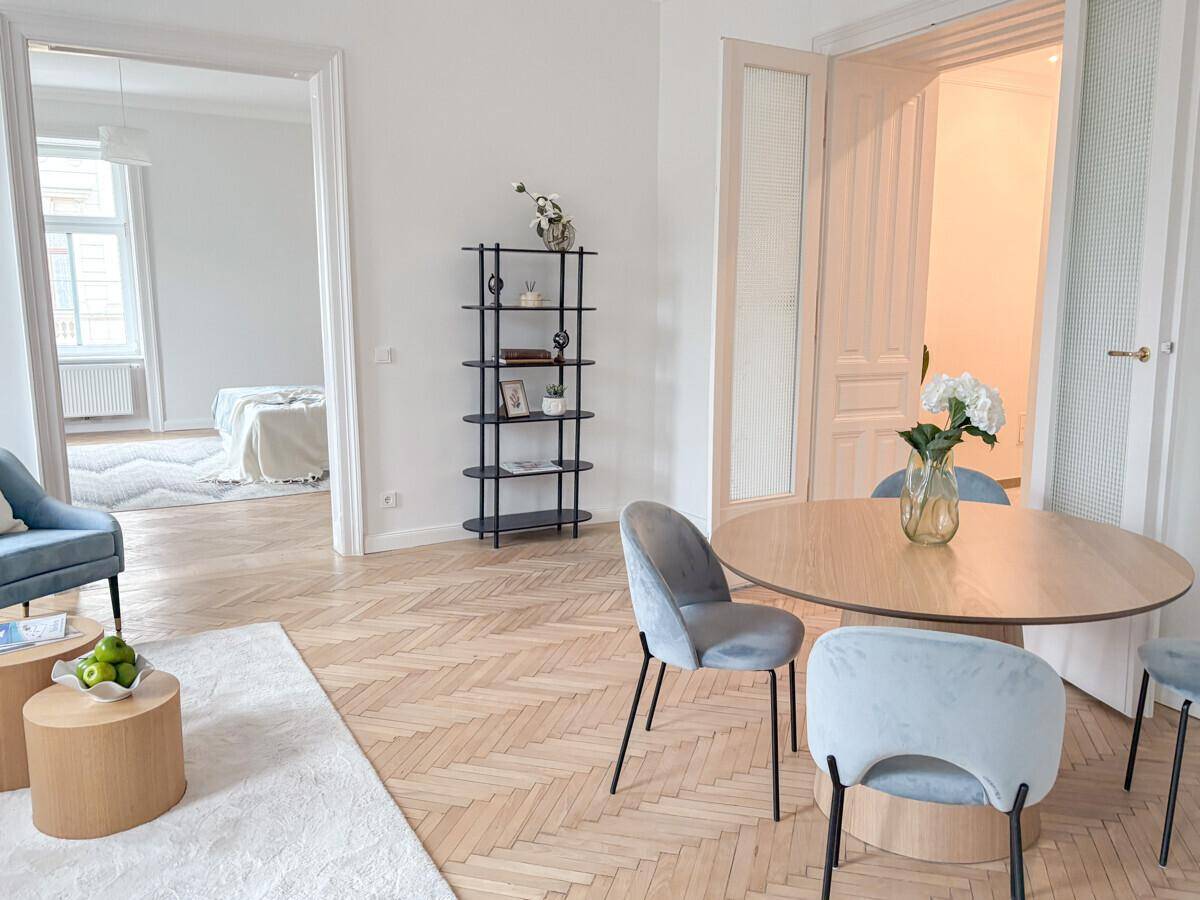 Offener Wohnbereich mit Esstisch, modernen Stühlen und Blick in ein weiteres Zimmer.