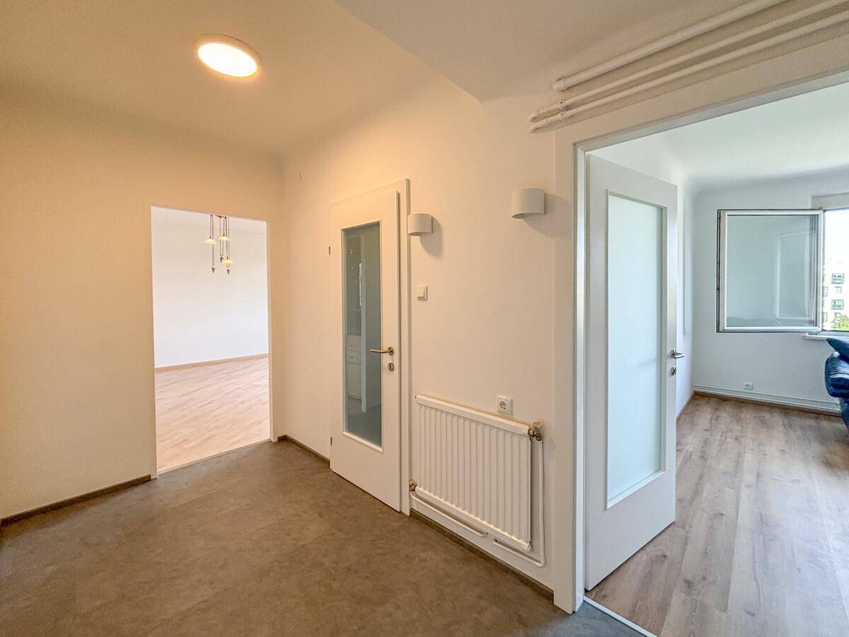 Heller Flur mit weiß gestrichenen Wänden, Heizkörper und Türen zu angrenzenden Räumen.