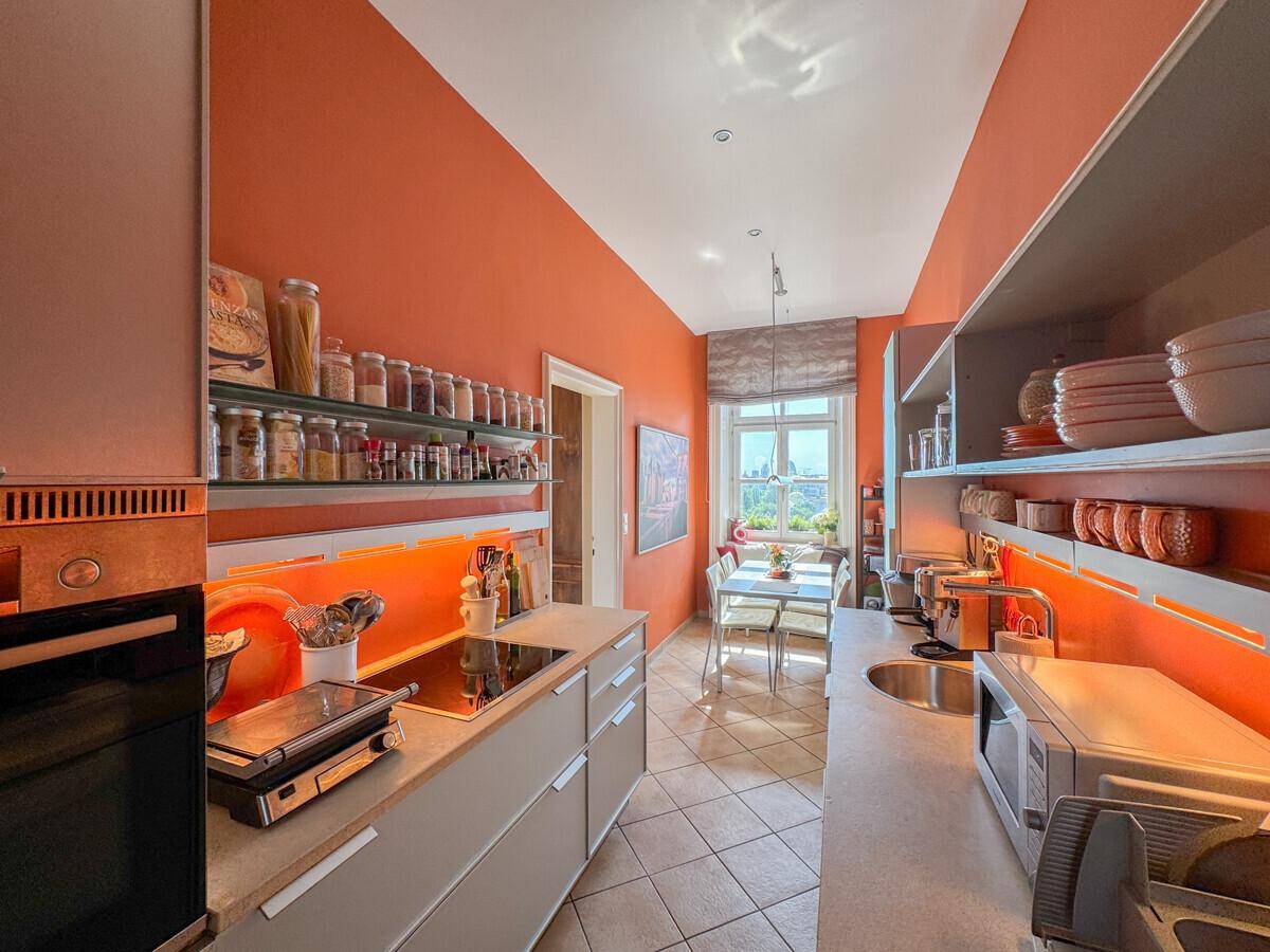 Funktionale Küche mit orangefarbenen Wänden, integrierten Geräten und viel Stauraum.