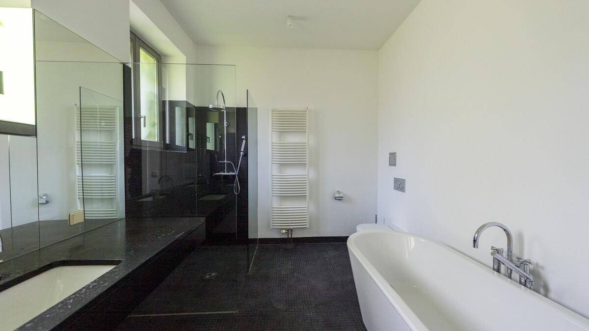 Modernes Badezimmer mit freistehender Badewanne, begehbarer Dusche und großem Fenster für Tageslicht.