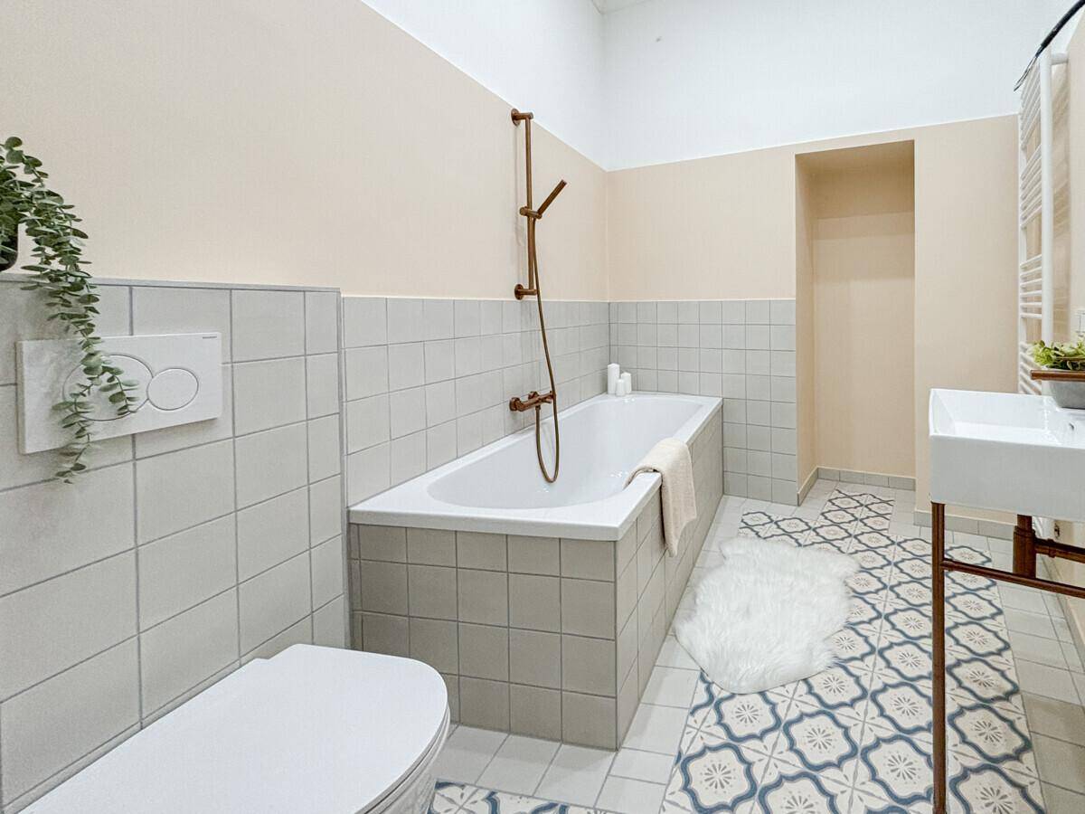 Modernes Badezimmer mit Badewanne, WC und dekorativen Bodenfliesen.