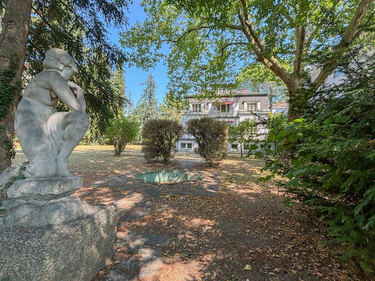 Skulptur in einem weitläufigen Gartenbereich mit altem Baumbestand und Teich.