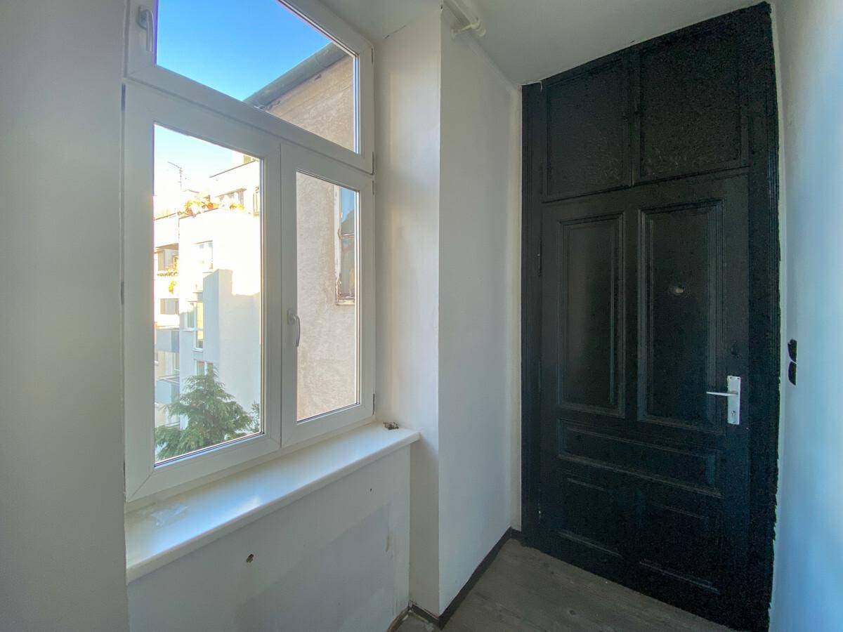 Heller Eingangsbereich mit einem großen Fenster und einer dunklen, traditionellen Tür.