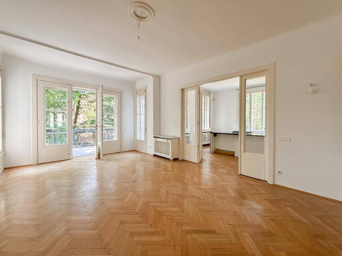 Lichtdurchflutetes Wohnzimmer mit Eichenparkett und Zugang zu weiteren Räumen.