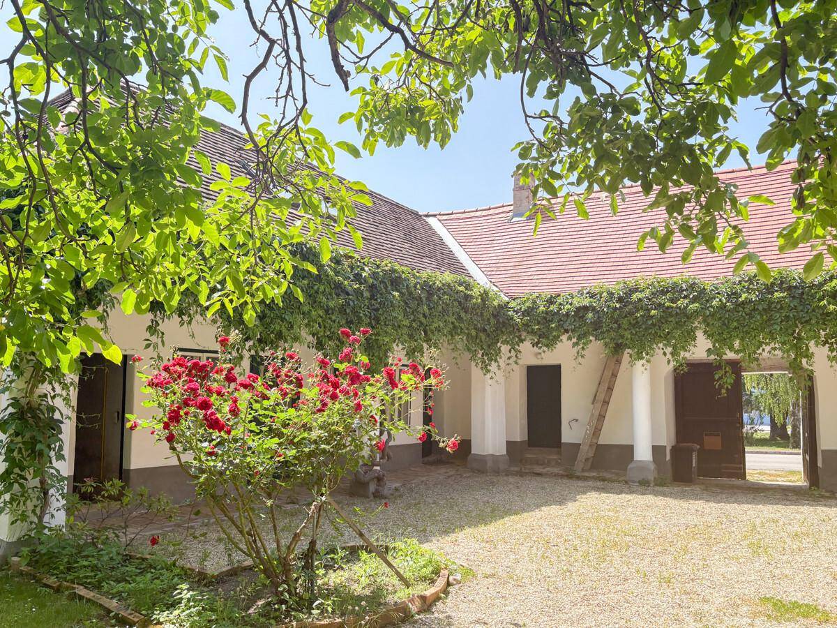 Idyllischer Innenhof mit üppiger Begrünung, roten Rosen und traditioneller Architektur.