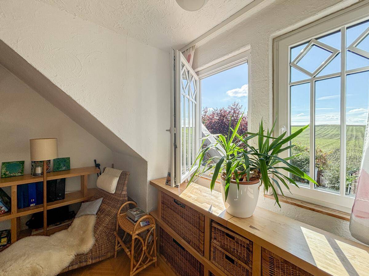 Gemütlicher Dachraum mit Schräge, Holzelementen und weitem Blick über die Felder.