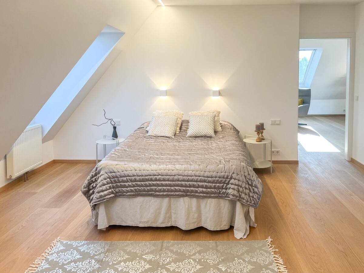 Ruhiges Schlafzimmer im Dachgeschoss mit Doppelbett, Holzboden und schrägen Wänden.