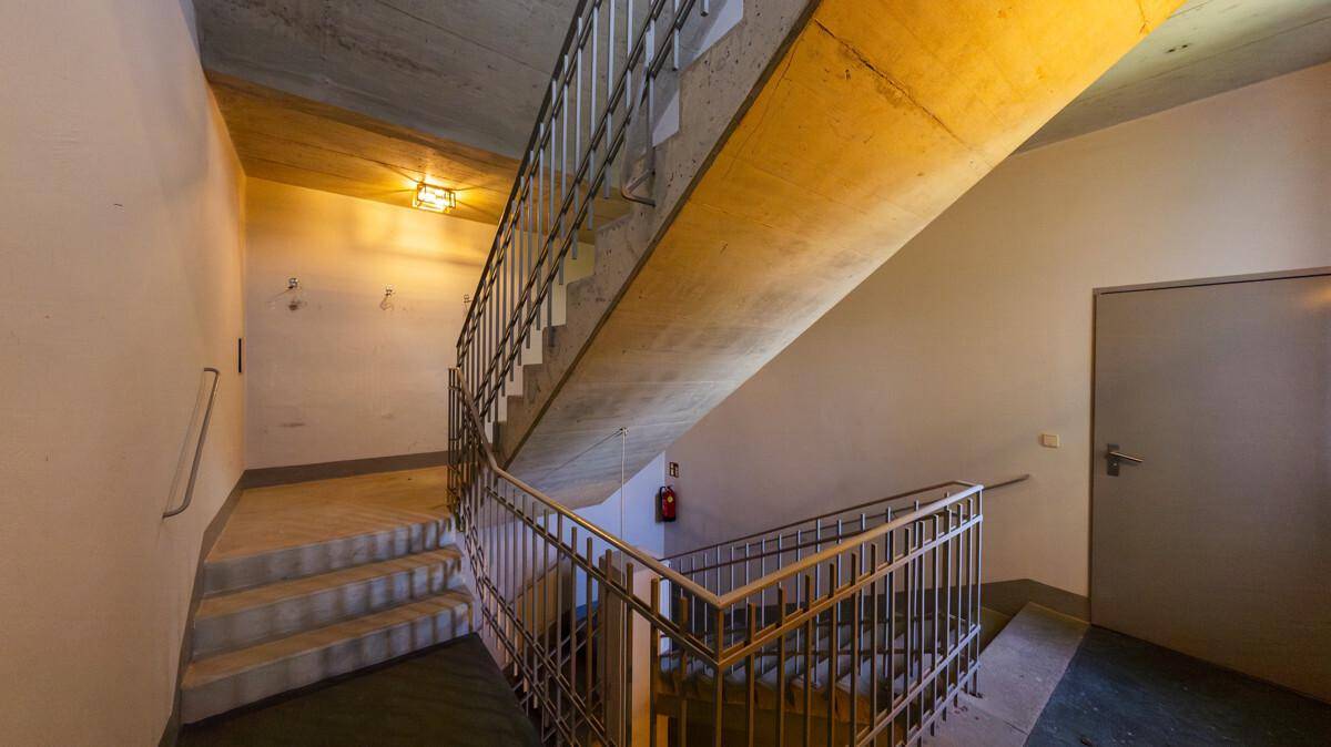 Geräumiges Treppenhaus mit Betonstufen und Metallgeländer, gut beleuchtet und funktional gestaltet.