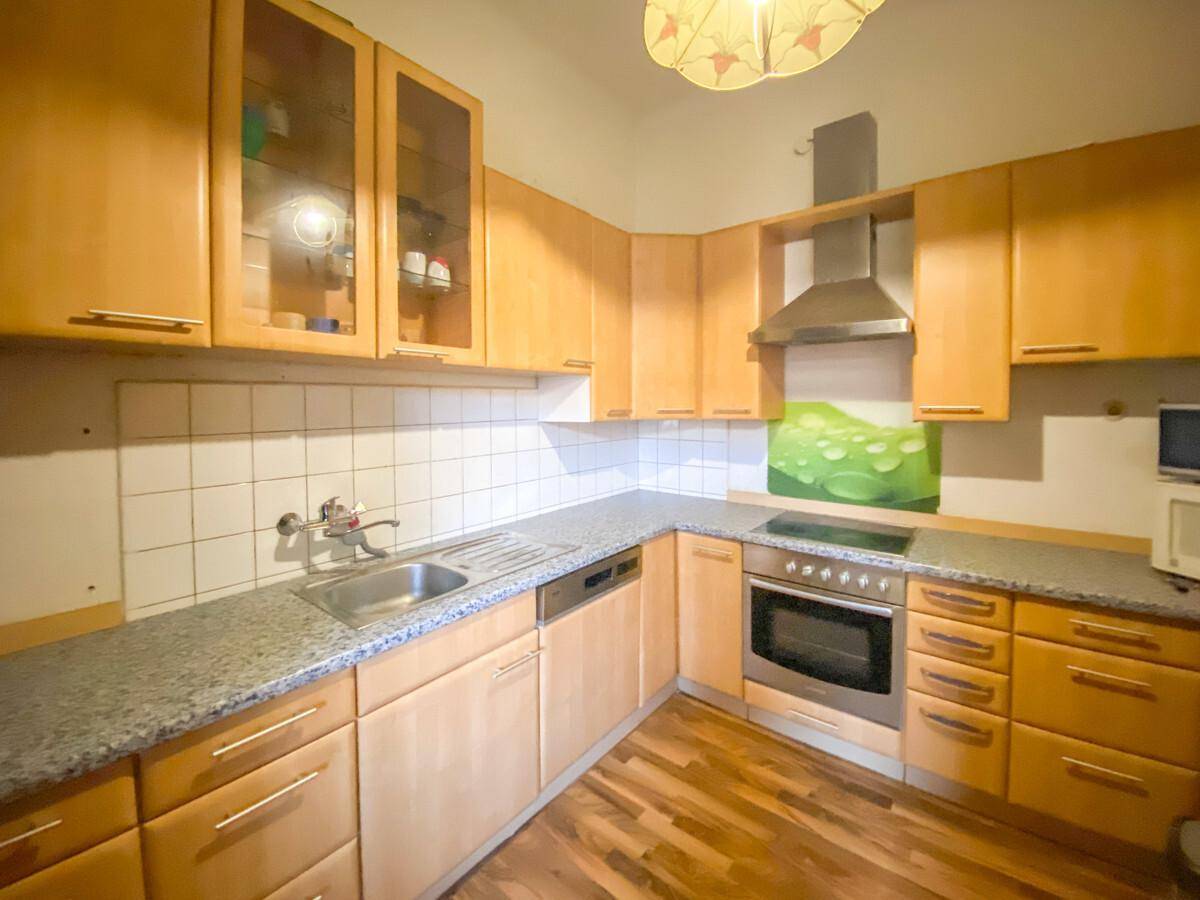 Funktionale Küche mit Holzschränken, Granitarbeitsplatte und integrierten Geräten.
