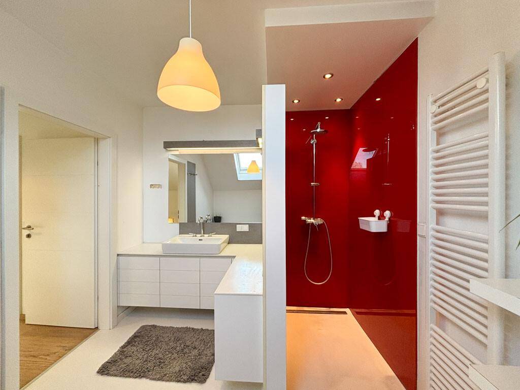 Modernes Badezimmer mit begehbarer Dusche, Einzelwaschbecken und roter Akzentwand.