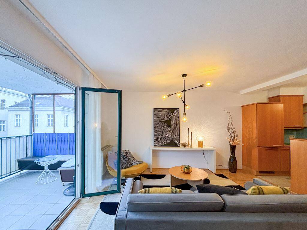 Helles Wohnzimmer mit modernem Dekor, Parkettboden und Zugang zu einem möblierten Balkon.