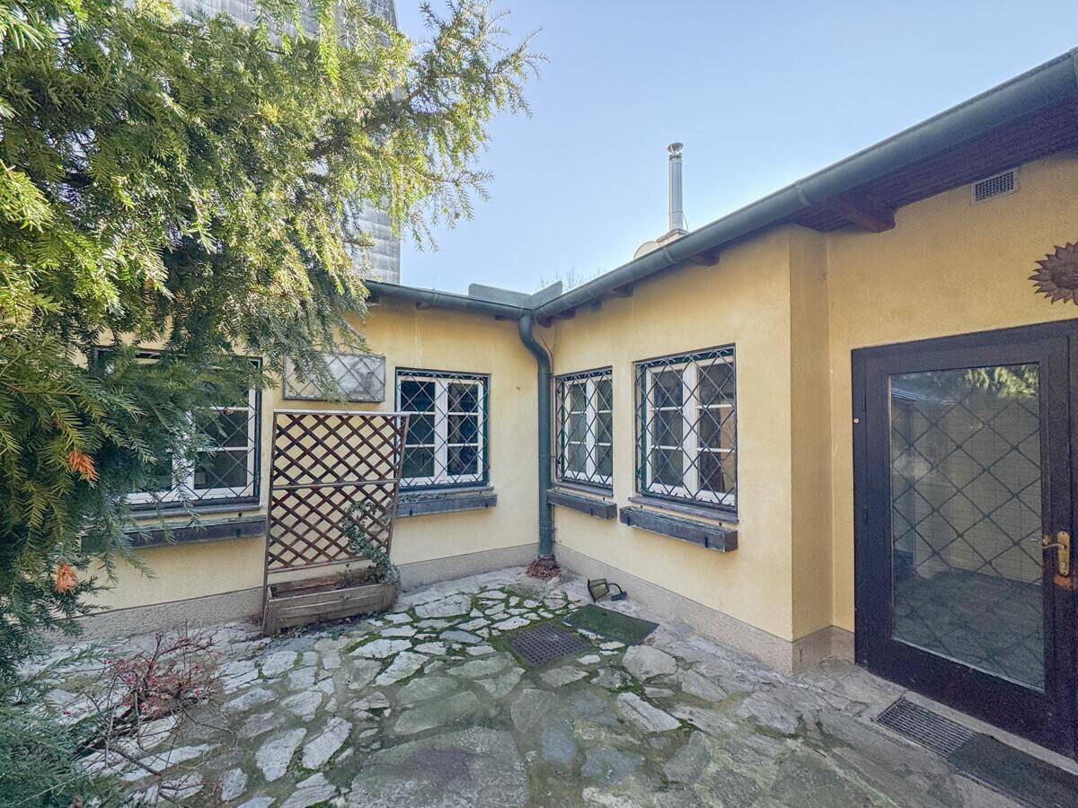 Kleiner, gepflasterter Innenhof mit Gitterfenstern und einer Tür, umgeben von gelben Fassaden.