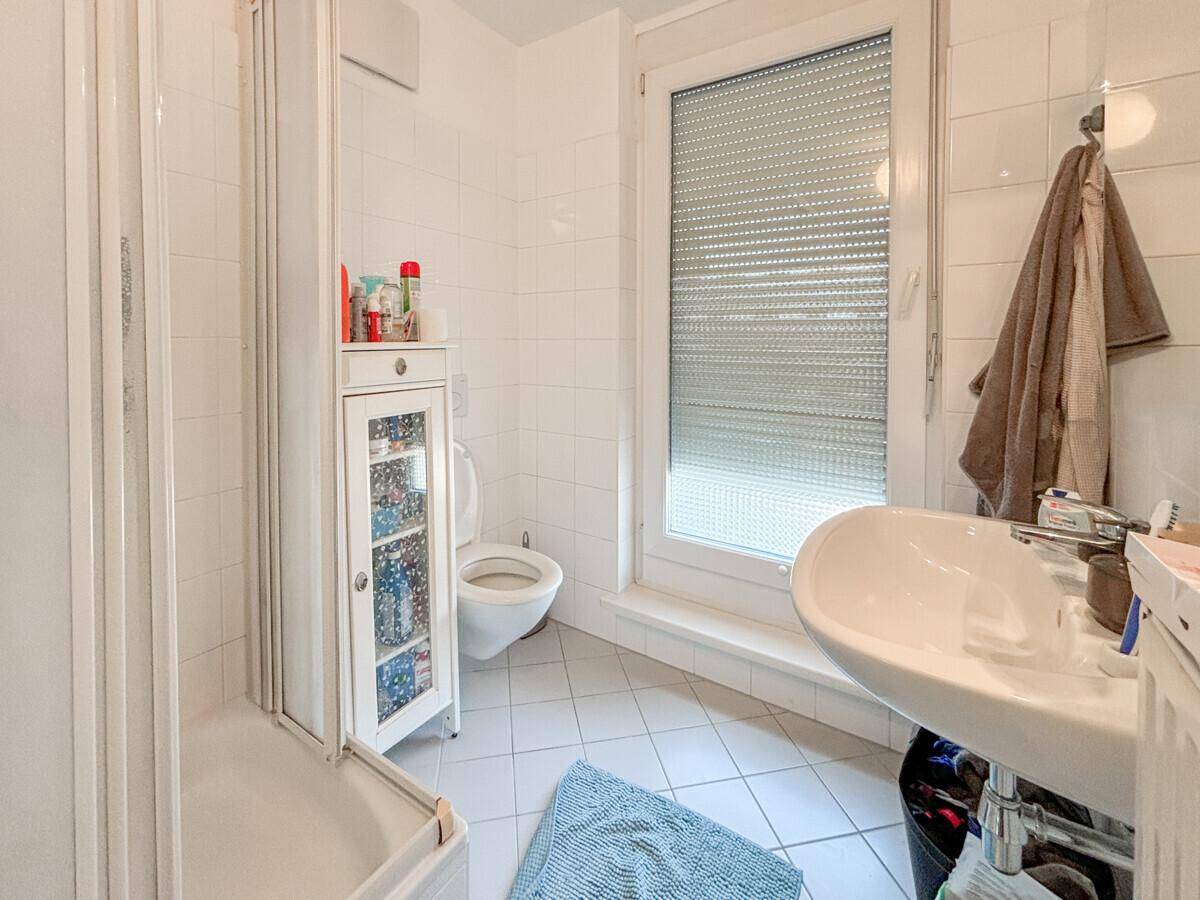 Badezimmer mit Duschkabine, Toilette, Waschbecken und einem Fenster für Belüftung.