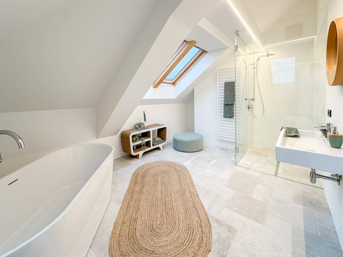 Elegantes Badezimmer mit freistehender Badewanne, ebenerdiger Dusche, Dachfenster und modernen Fliesen.