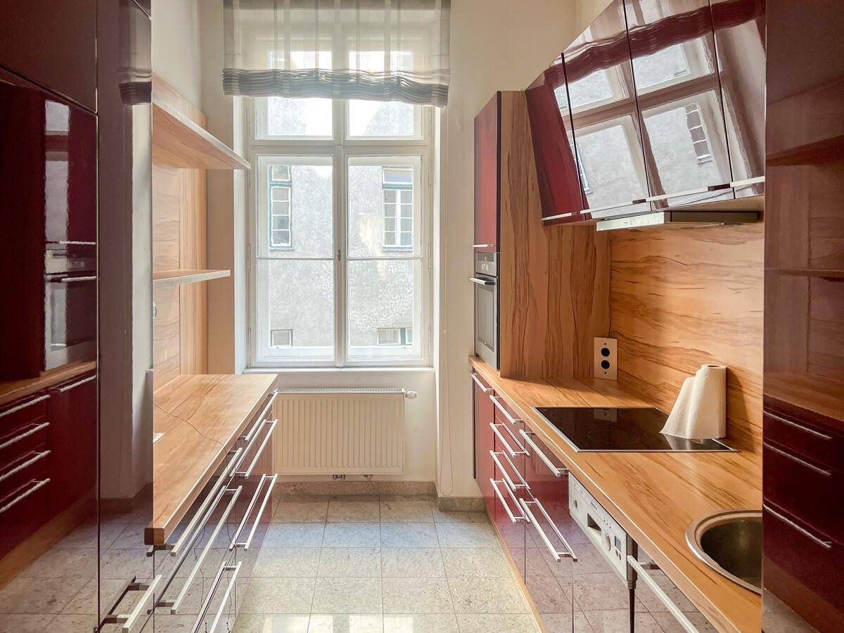 Moderne Küche mit roten Hochglanzschränken, Holzarbeitsplatten und Fenster.