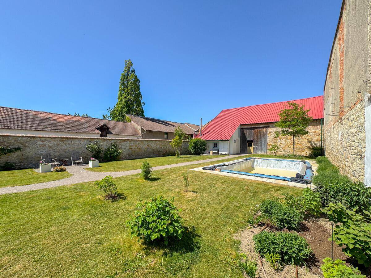 Weitläufiger Gartenbereich mit einem Pool und Blick auf die historische Scheune mit rotem Dach.