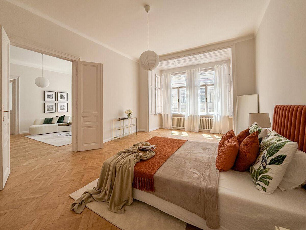 Gemütliches Schlafzimmer mit Holzboden, großem Bett und Zugang zum Wohnbereich.