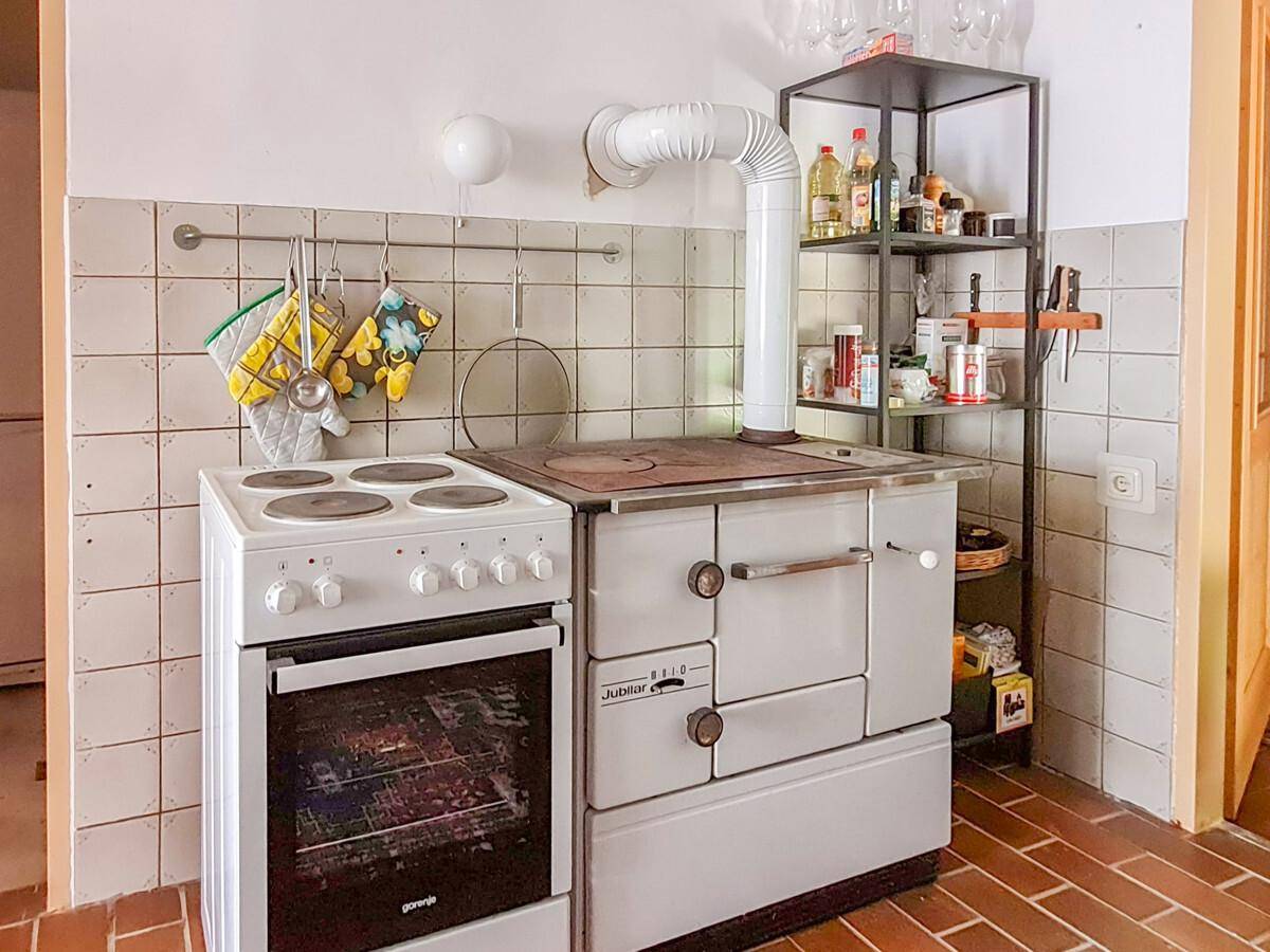 Traditionelle Küche mit einem Elektroherd, einem Holzofen und gefliesten Wänden.