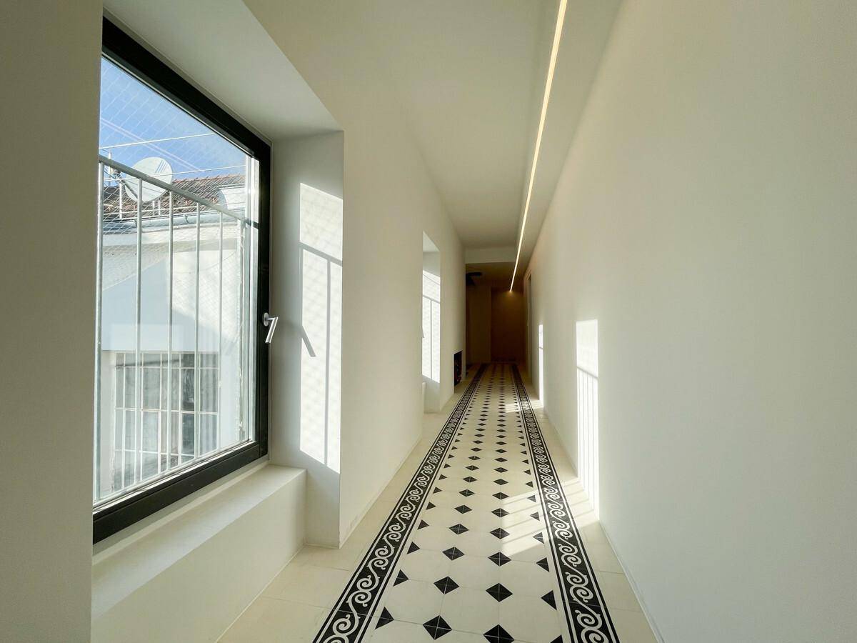 Langer, heller Flur mit modernem Fliesenboden und natürlichem Lichteinfall durch Fenster.