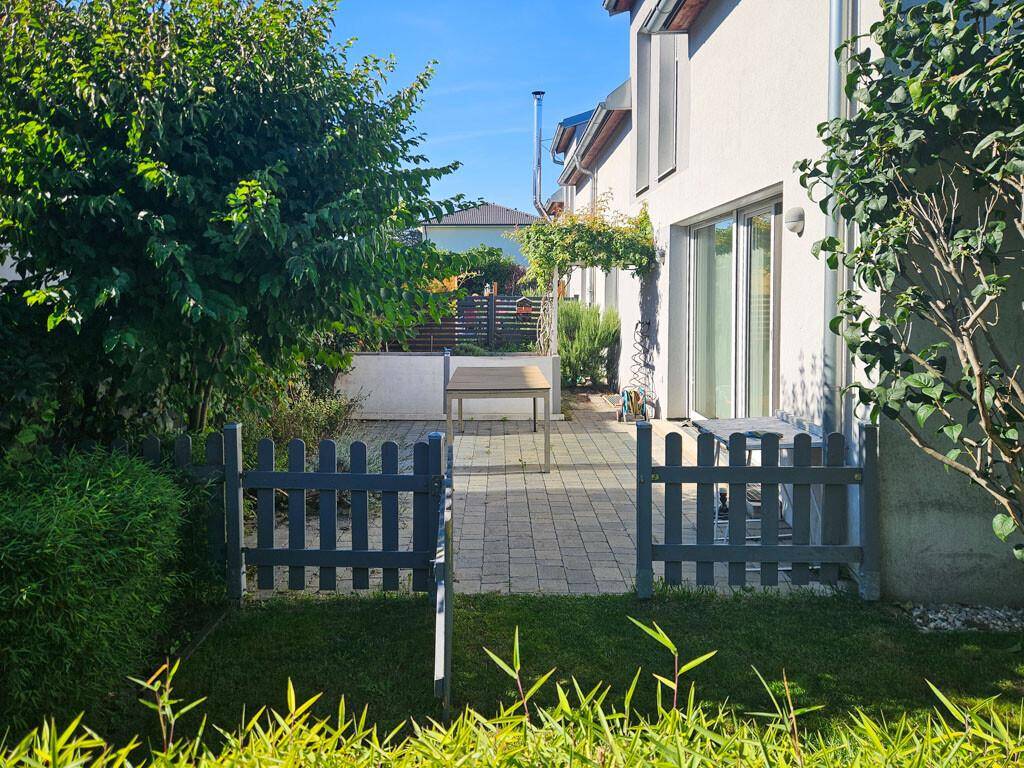 Kleiner Gartenbereich mit Zaun und Zugang zur gepflasterten Terrasse des Hauses.