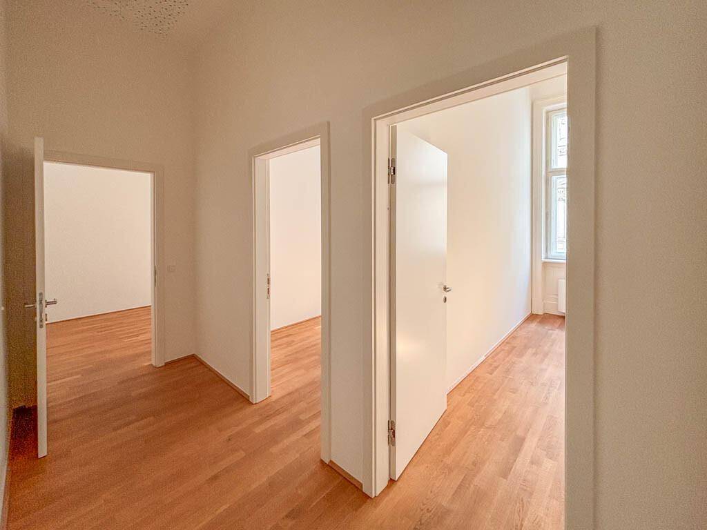 Heller Flur mit Holzboden und mehreren offenen Türen, die den Blick in angrenzende Räume freigeben.