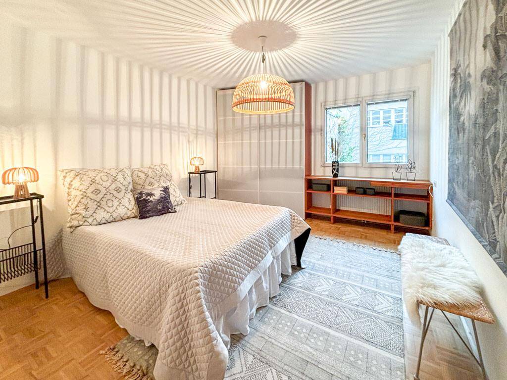 Gemütliches Schlafzimmer mit Doppelbett, Holzboden und dekorativer Deckenleuchte.