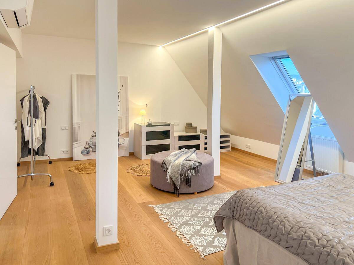 Helles Schlafzimmer im Dachgeschoss mit Holzboden, moderner Beleuchtung und viel Platz.