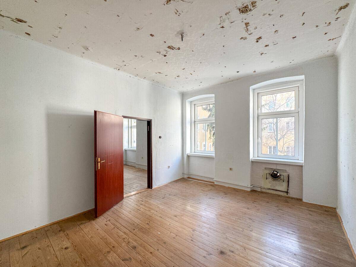 Leeres Zimmer mit Dielenboden und offener Verbindung zu einem weiteren Raum, vielseitig nutzbar.